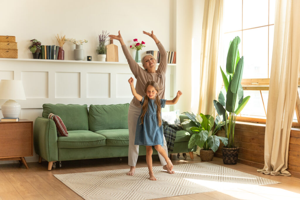 Oma und Enkelin tanzen gemeinsam im Wohnzimmer